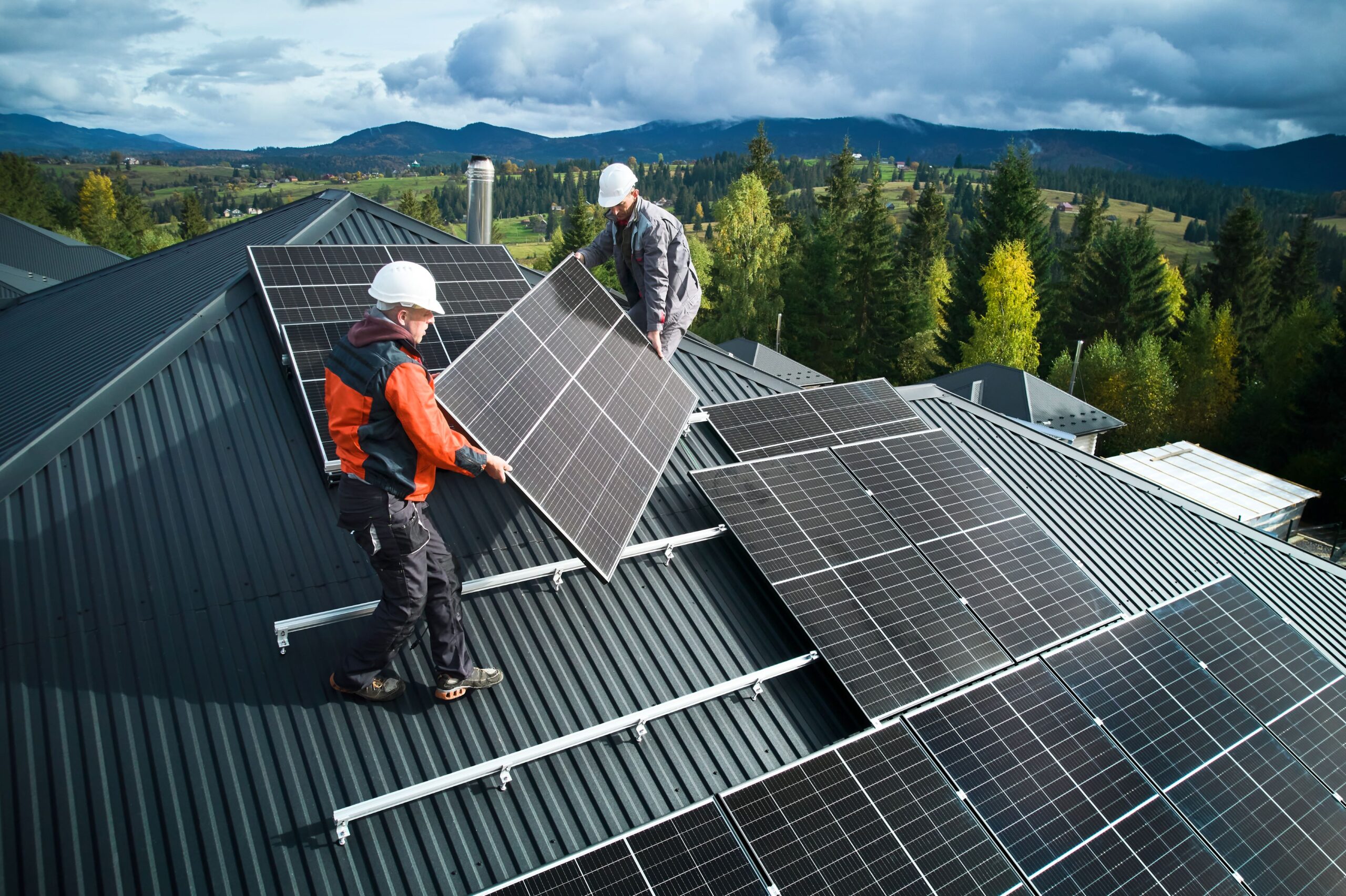 Zwei Personen bauen eine Solaranlage auf einem Dach zusammem.