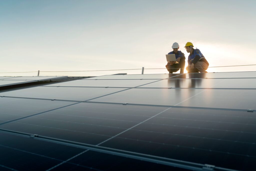 Zwei Personen stehen auf einem Dach wo eine Solaranlage drauf angebracht ist.