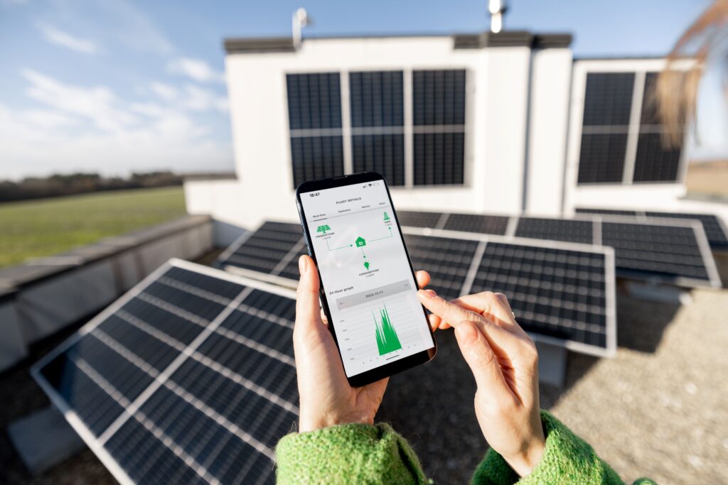 Eine Person hält ein Handy in der Hand wo sie den gewonnen Strom der Solaranlage sehen kann