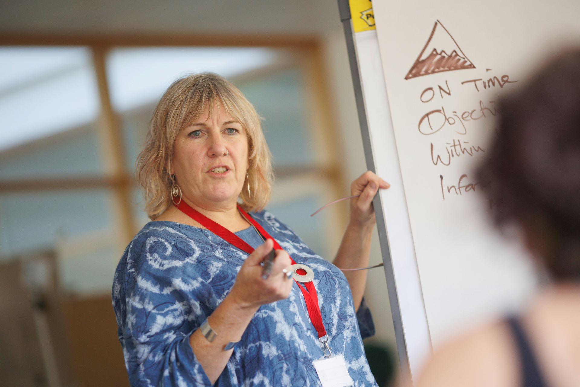 Erfahrene Pädagogin erklärt Inhalte vor einem Whiteboard während eines Workshops oder einer Weiterbildung