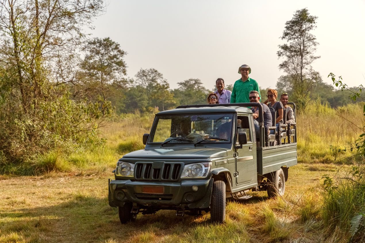 Eine Gruppe von Touristen sitzt in einem offenen Safari-Fahrzeug, bereit, die Wildnis von Tansania zu erkunden – ein Abenteuer auf einer Tansania Safari.