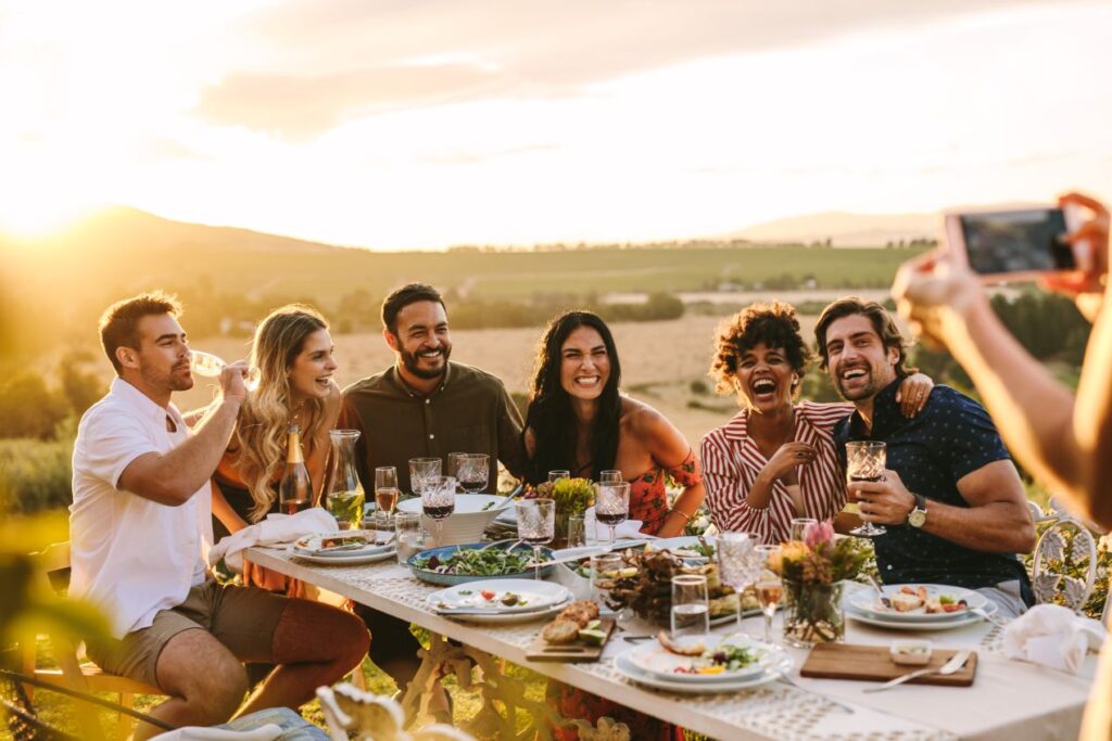 Gruppe von Freunden bei einer sommerlichen Gartenparty, gedeckter Tisch mit Speisen, geeignet für Feiern unter einem Lagerzelt wasserdicht